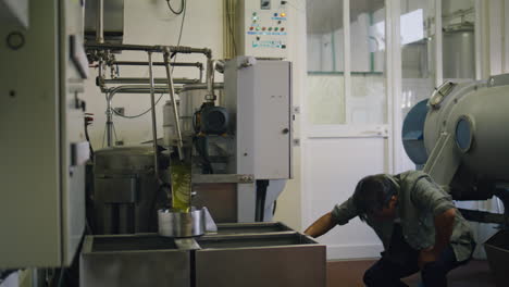 Serious-man-turning-press-machine-at-fabric-closeup.-Worker-producing-olive-oil