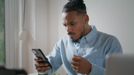 Annoyed-guy-using-mobile-phone-at-flat.-Irritated-man-looking-smartphone-screen