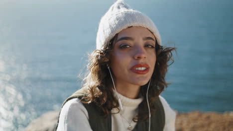 Portrait-ocean-girl-listening-music-in-earphones-vertical.-Traveler-look-camera