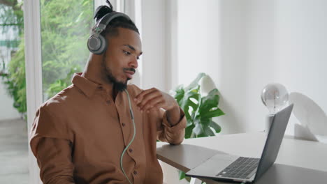 Headphones-freelancer-talking-online-flat-closeup.-Man-holding-laptop-video-call