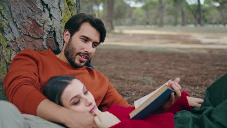 Lovely-couple-lying-park-with-book-closeup.-Man-reading-aloud-for-calm-woman.