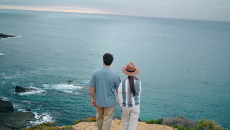 Romantic-couple-walking-sea-shore-back-view.-Pair-looking-on-picturesque-ocean.