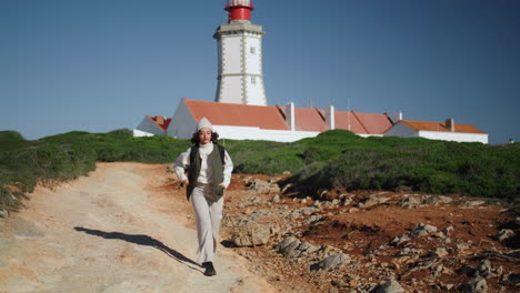 Active-girl-walking-lighthouse-landscape-vertical-shot.-Happy-tourist-exploring