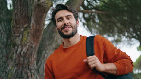 Handsome-bearded-man-vertical-portrait-smiling-in-park.-Guy-holding-backpack