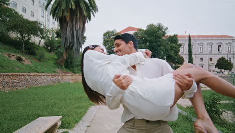 Excited-lovers-rejoicing-in-garden.-Latina-man-carrying-laughing-woman-at-hands