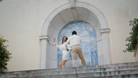 Excited-lovers-running-stairs.-Positive-man-woman-holding-hands-in-azulejo-place