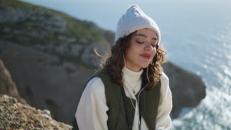 Satisfied-woman-listening-music-on-cliff-edge.-Happy-girl-closing-eyes-resting
