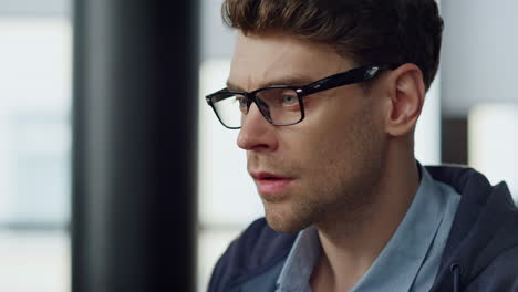 Focused-it-guy-checking-online-report-closeup.-Pensive-businessman-in-glasses