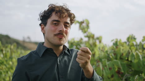 Portrait-man-eating-grapes-on-vineyard.-Winegrower-checking-plantation-harvest.