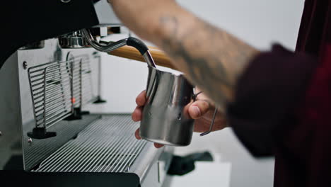 Barista-hands-preparing-latte-drink-on-professional-coffee-machine-close-up.