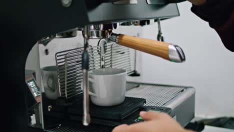 Barista-putting-portafilter-coffee-machine-for-making-hot-drink-close-up.
