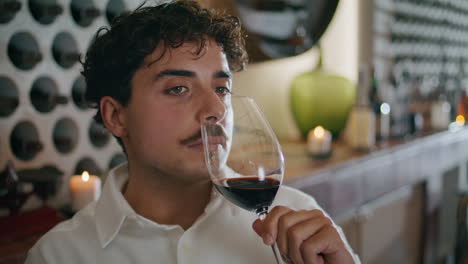 Man-sniffing-red-wine-poured-in-glass-closeup.-Serious-sommelier-enjoying-smell.