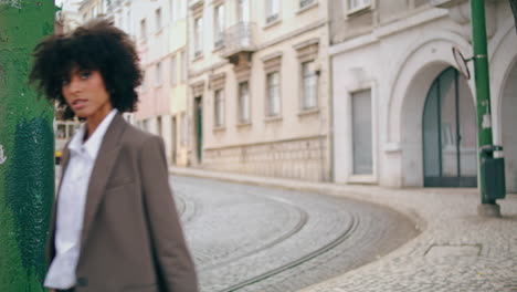 Girl-walking-cobblestone-road-old-city-with-tram-on-backdrop.-Woman-going-street