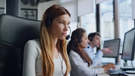 Professional-service-agent-talk-client-in-headset.-Focused-woman-typing-computer