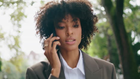 Woman-answering-phone-call-walking-city-park-closeup.-Lady-talking-on-smartphone