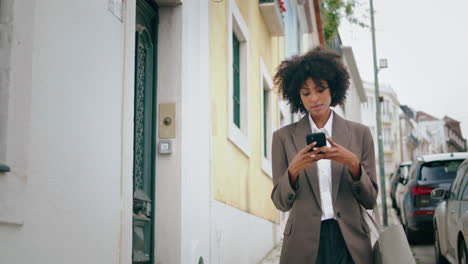 Mujer-Usando-Un-Teléfono-Inteligente-Caminando-Por-La-Calle-De-La-Ciudad.-Chica-Afroamericana-Mirando-Teléfono.