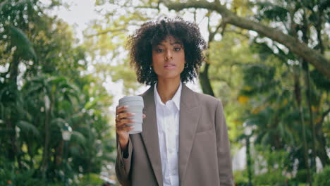 Business-lady-going-park-alley-with-coffee-closeup.-Girl-walking-looking-phone.