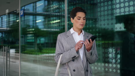 Businesswoman-sending-phone-message-at-downtown-building.-Happy-woman-end-call