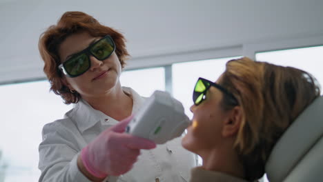 Cosmetologist-dermatologist-using-laser-device-for-lifting-client-skin-close-up.