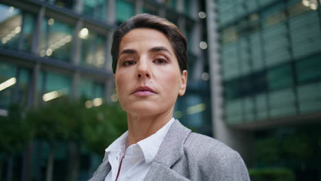 Portrait-mature-businesswoman-posing-at-glass-office-facade.-Serious-female-ceo