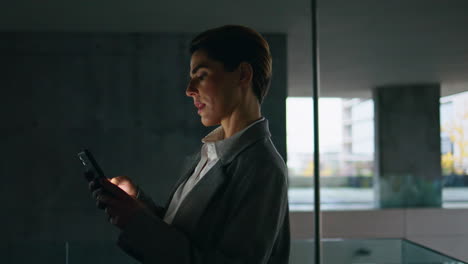 Dark-woman-using-smartphone-on-office-terrace.-Focused-businesswoman-scrolling