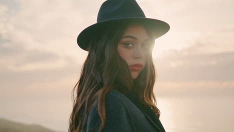 Relaxed-girl-traveler-posing-in-front-beautiful-sunset-wearing-hat-close-up.