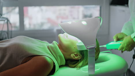 Cosmetologist-applying-facial-treatment-led-mask-in-clinic-closeup.-Phototherapy