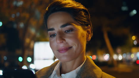 Woman-browsing-night-city-closeup.-Smiling-executive-in-smartphone-screen-light