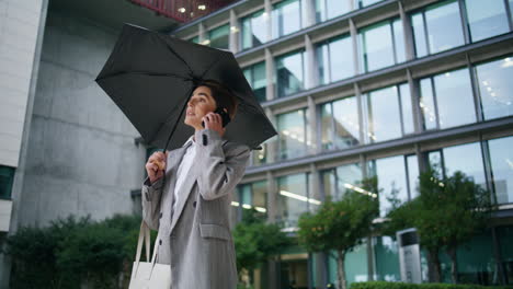 Businesswoman-making-phone-call-on-rainy-day.-Office-employee-talk-at-downtown