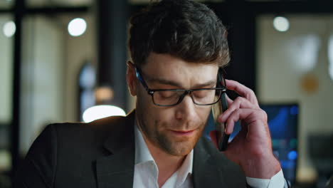 Closeup-businessman-listening-mobile-phone-in-dark-office.-Focused-man-trader