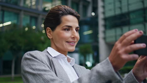 Corporate-woman-film-video-on-mobile-phone-closeup.-Happy-relaxed-businesswoman
