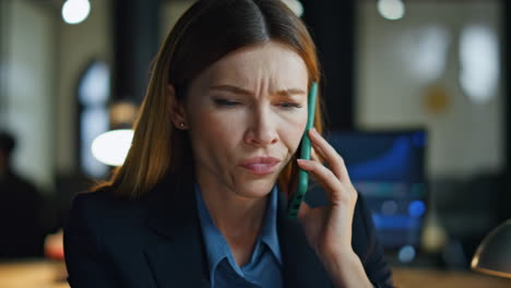 Serious-woman-talk-mobile-phone-in-office-closeup.-Nervous-businesswoman-discuss