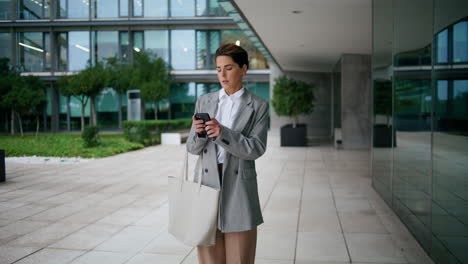 Female-executive-type-cellphone-at-downtown-business-center.-Focused-woman-hold