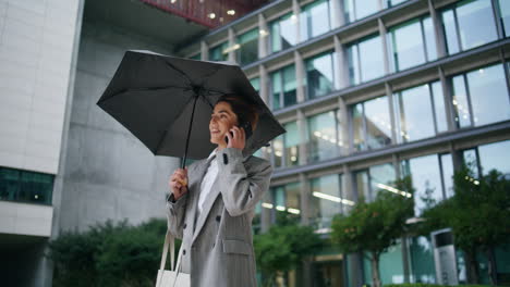 Happy-worker-speaking-phone-on-rainy-downtown-district.-Joyful-manager-end-call