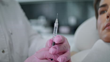 Hands-holding-syringe-collagen-before-injecting-in-woman-client-face-close-up.