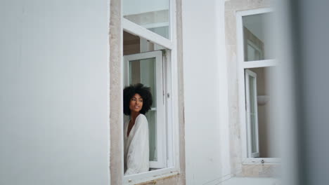 Tender-model-leaning-window-frame-white-house.-Curly-woman-posing-camera-alone