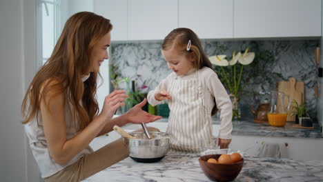 Loving-mother-teach-daughter-bake-in-kitchen.-Friendly-family-cooking-together