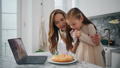 Birthday-girl-blowing-candles-kitchen-closeup.-Family-celebrating-virtual-chat