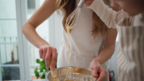 Mom-daughter-kneading-dough-in-bowl-indoors-close-up.-Laughing-woman-mixing