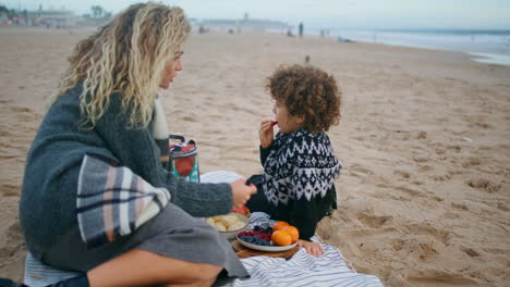 Mom-enjoying-son-picnic-on-autumn-ocean-shore.-Family-spending-time-together.