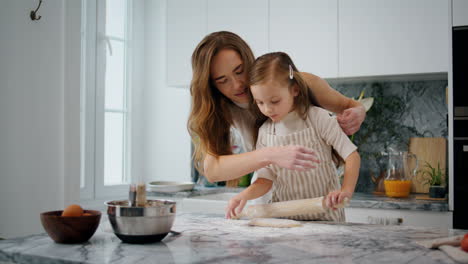 Caring-mother-rolling-sleeves-to-daughter-at-kitchen-closeup.-Kid-helping-parent