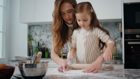 Involved-family-making-dough-at-home-close-up.-Tender-mother-helping-child