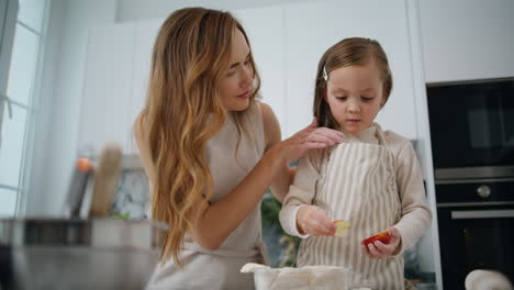 Cute-child-making-apple-pie-with-mommy-at-home.-Mother-straightens-daughter-hair