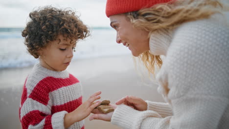 Smiling-mom-teaching-kid-at-seaside-closeup.-Cute-little-boy-counting-stones