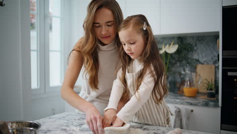 Mom-daughter-putting-dough-to-baking-form-indoors-close-up.-Girl-helping-parent