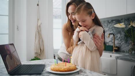 Child-birthday-videocall-celebration.-Girl-holding-toy-preparing-blowing-candles
