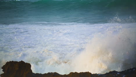 White-sea-waves-hitting-rocks-beach-in-slow-motion.-Foaming-stormy-ocean-rolling