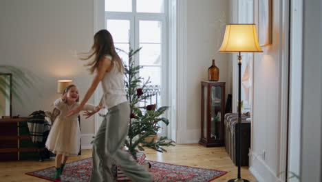Active-family-playing-at-New-Year-tree-room.-Mother-running-away-from-daughter