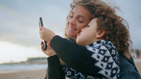Smiling-parent-taking-selfie-with-adorable-curly-son-closeup.-Happy-family-rest