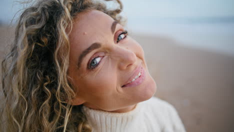 Romantic-woman-posing-beach-on-autumn-weekend-closeup.-Smiling-curly-model-enjoy